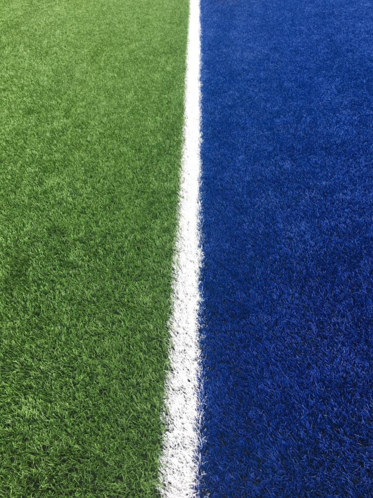 Ligne blanche séparant une zone verte d'une zone bleue sur un terrain de sport.