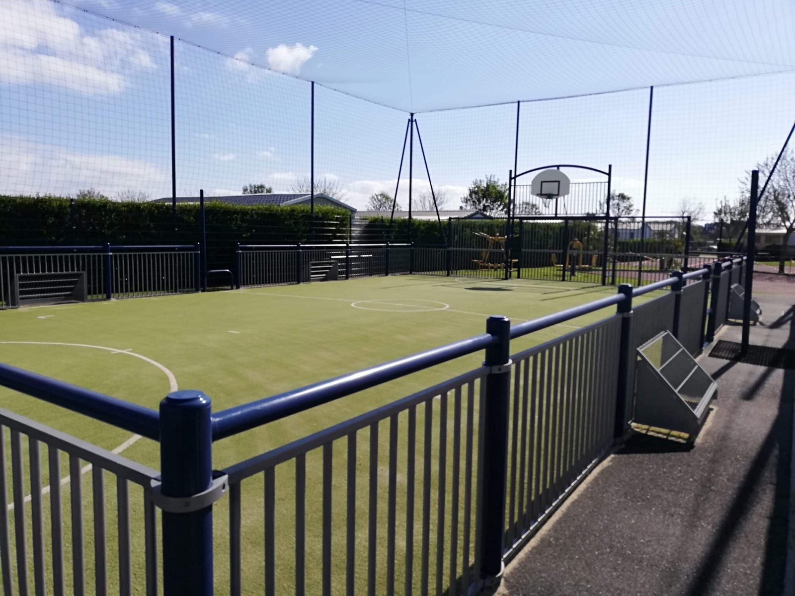 Petit terrain multisport avec clôture et panneaux de basket.